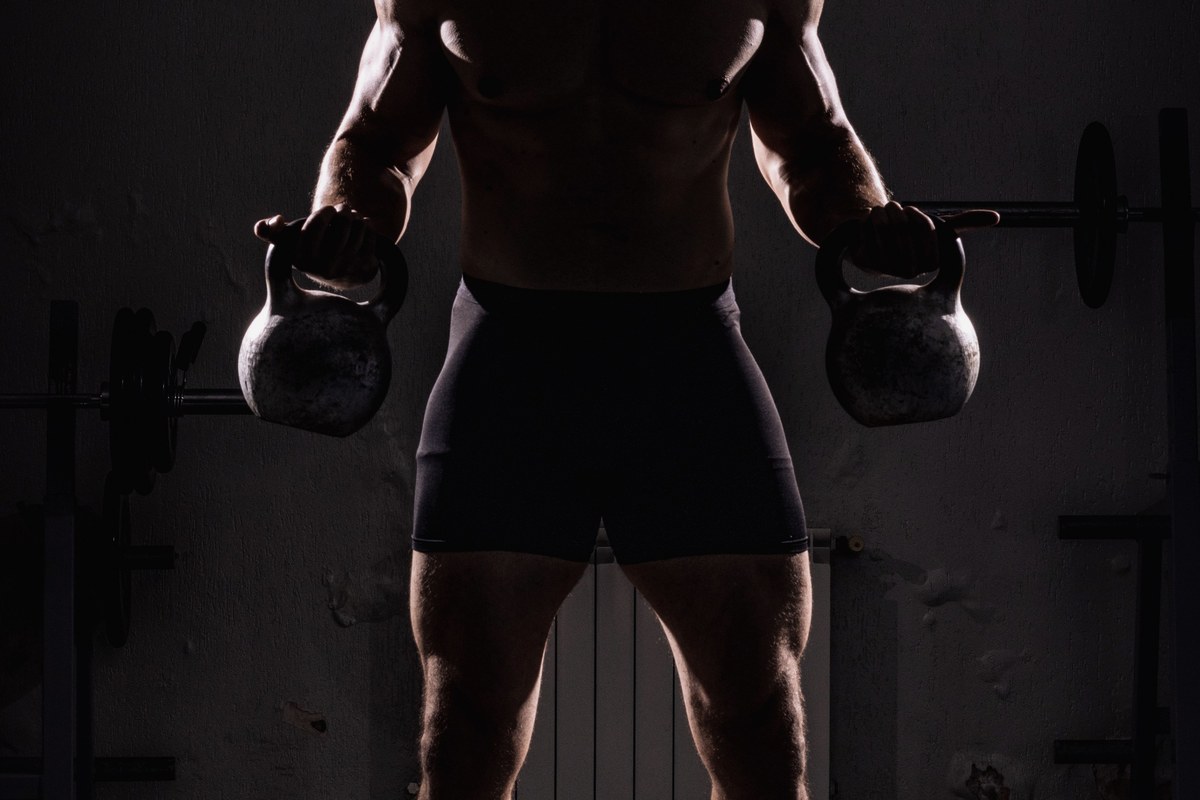 Man training with heavy weights in a dark gym