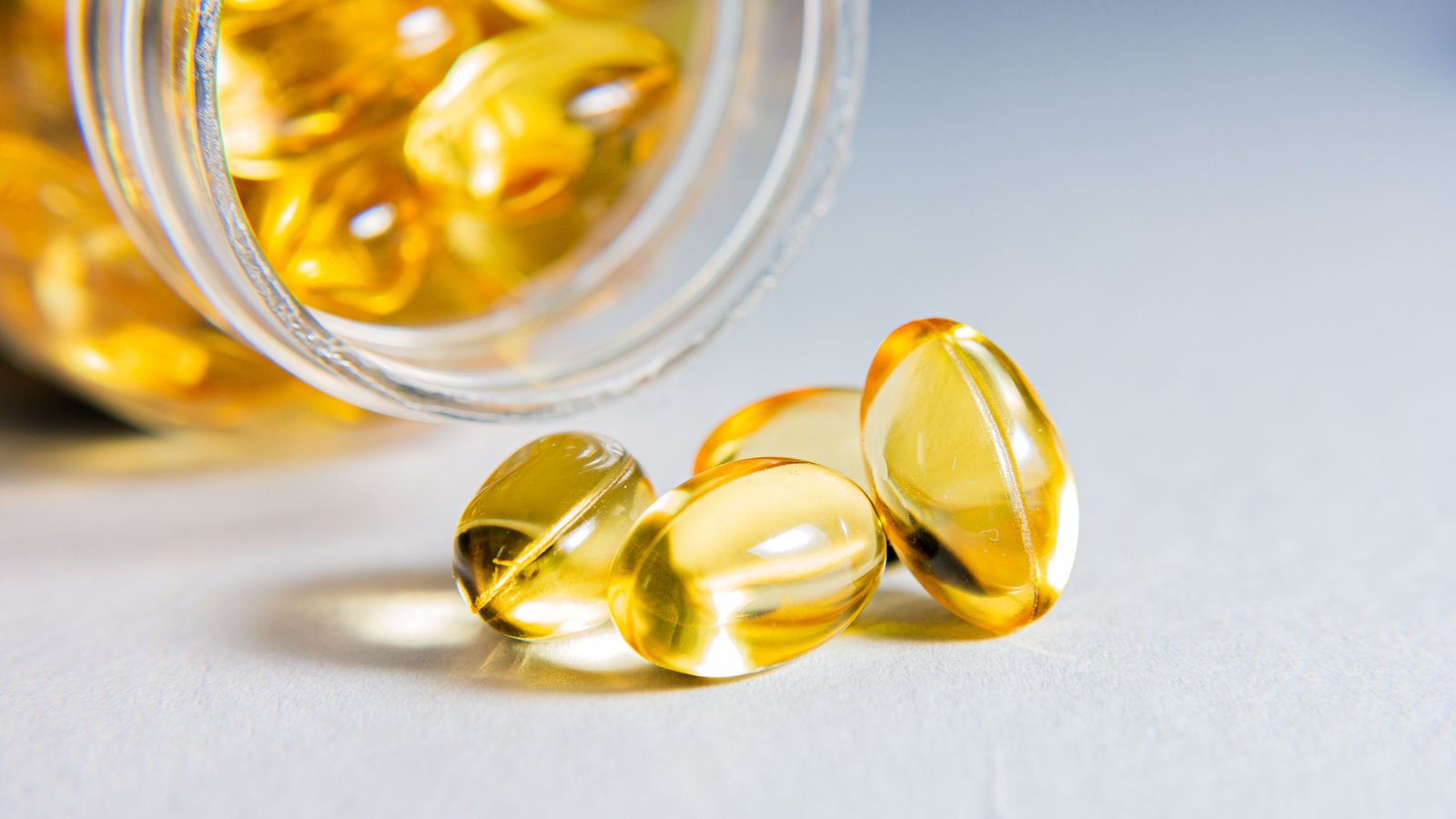 Omega-3 softgels spilling from a jar