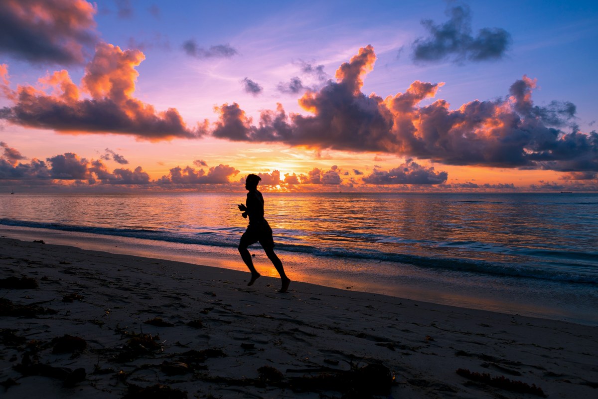 A lone runner at sunrise on an empty beach