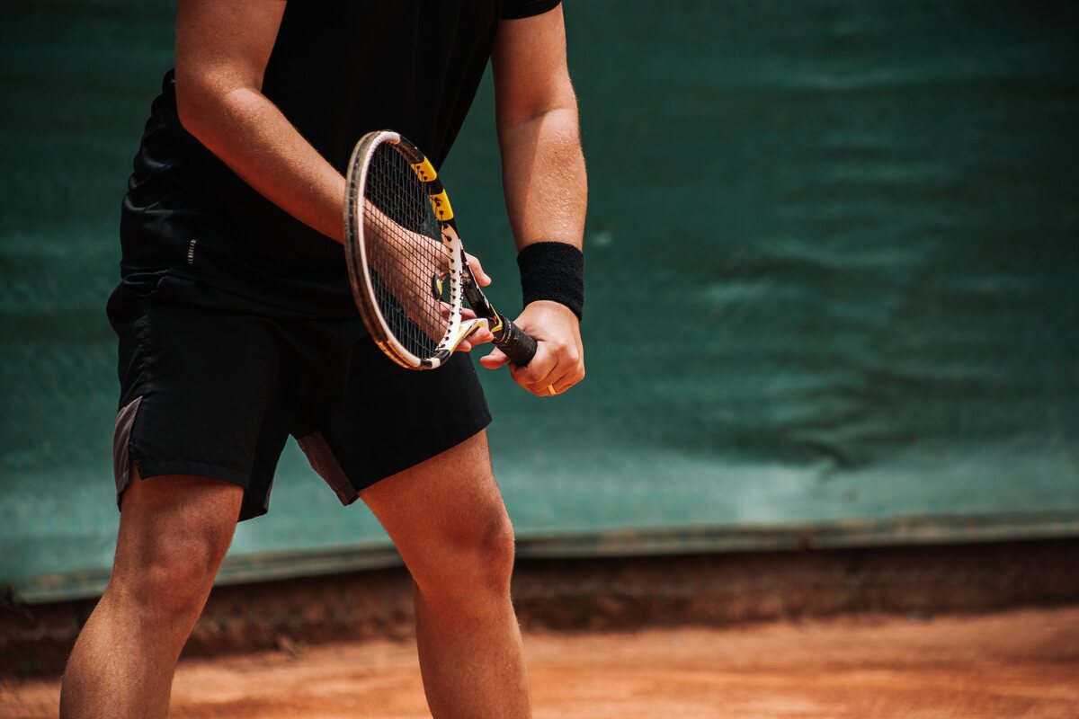 A tennis player mid-point on a clay court